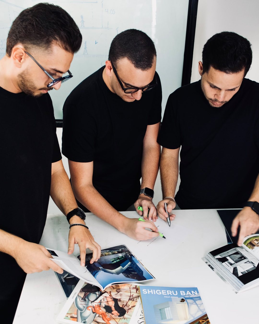 Los tres arquitectos de Caraqueña trabajando sobre la mesa con bocetos y libros de arquitectura